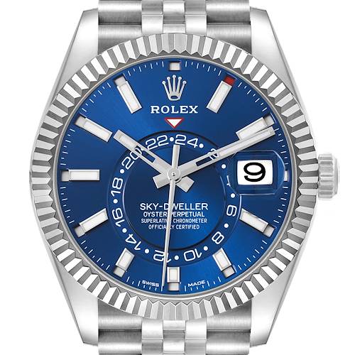 The Rolex Sky-Dweller is shown from a front angle, highlighting the blue dial, fluted bezel, hands, date window, and part of the bracelet.