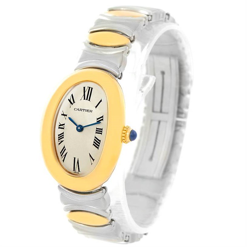 The Cartier Baignoire watch is shown at a front angle, displaying its oval dial, Roman numerals, and two-toned bracelet.