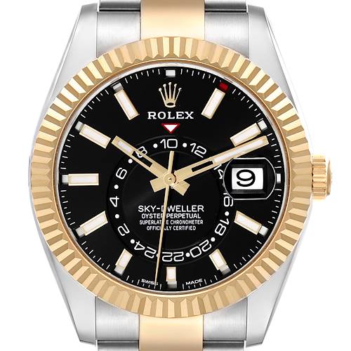 The image shows a front view of the Rolex Sky-Dweller watch, highlighting the black dial, gold fluted bezel, and date display.