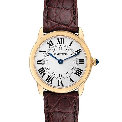 The Cartier Ronde watch is shown from a top-down angle, displaying the face, Roman numerals, and brown leather strap.