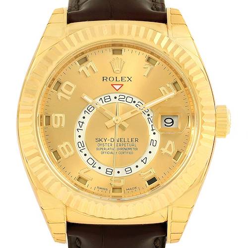 The image shows a front view of a Rolex Sky-Dweller watch, highlighting the gold dial, fluted bezel, and the date window.