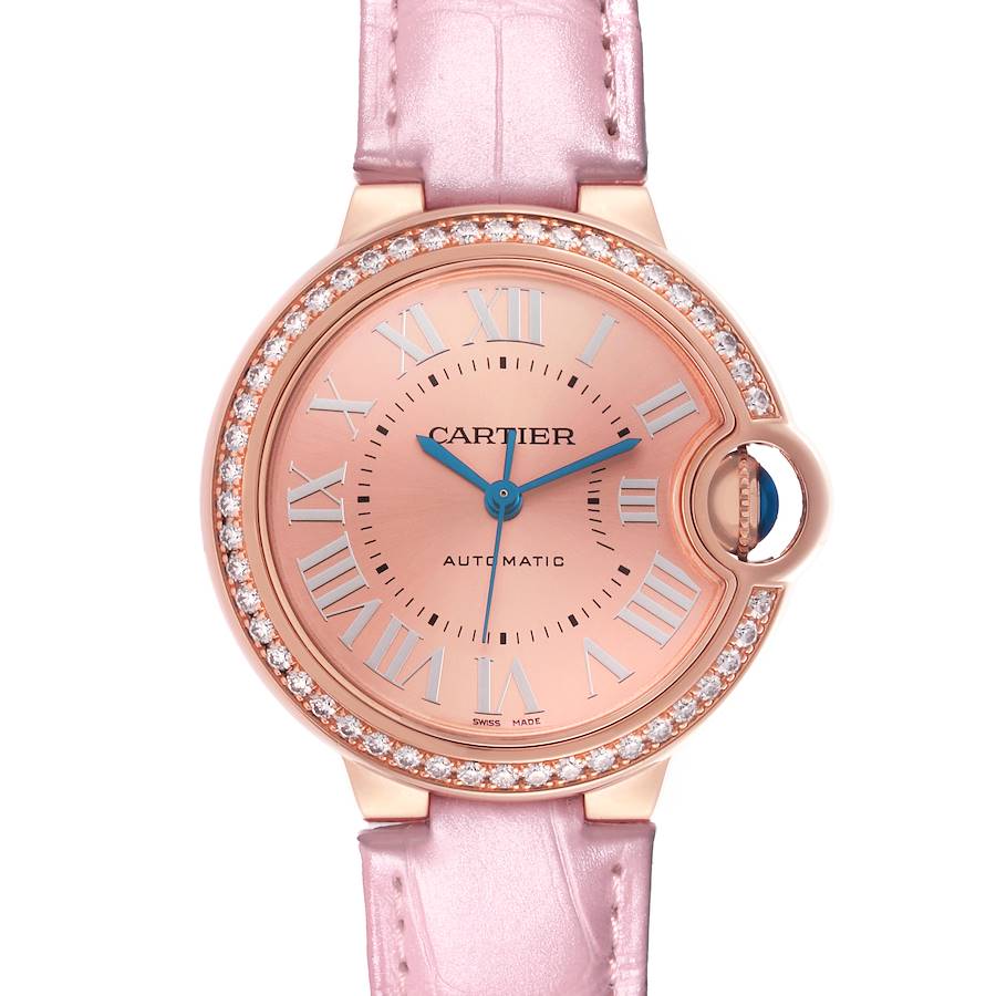 The Cartier Ballon Bleu watch is shown from a top view, highlighting its pink dial, diamond-set bezel, and pink strap.