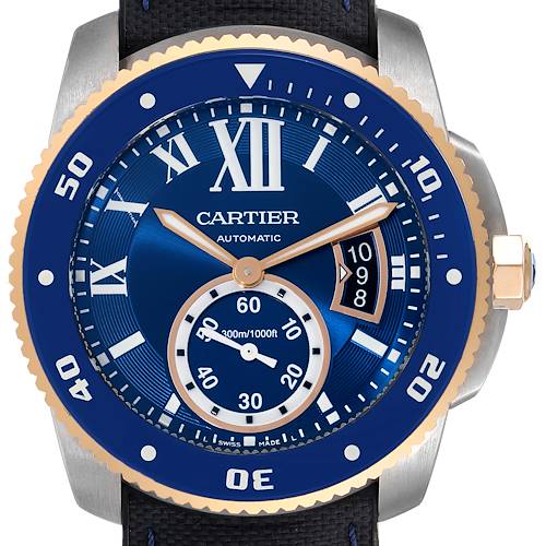 The image shows a frontal view of the Calibre de Cartier model by Cartier, highlighting its blue dial, bezel, and automatic movement indicators.